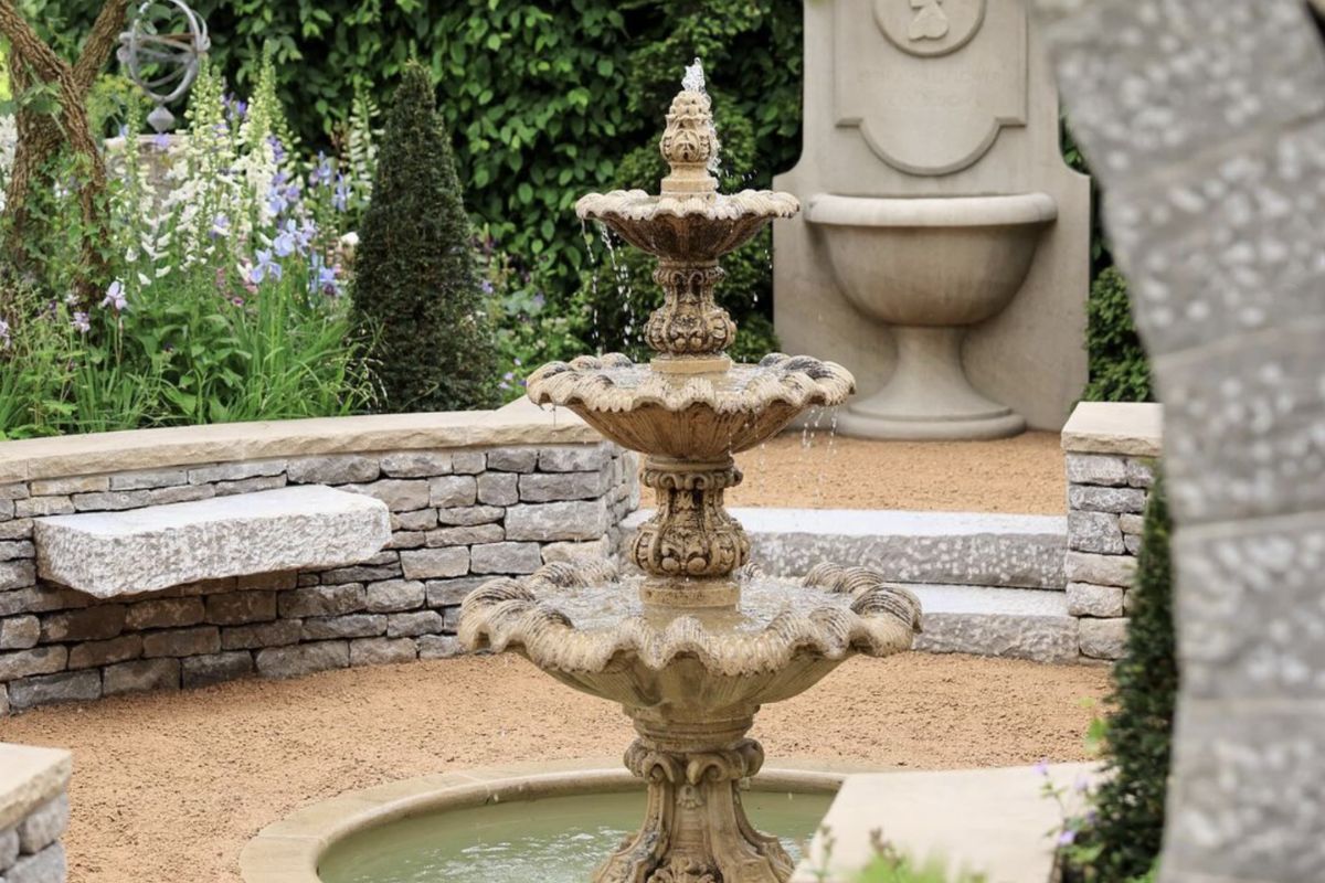 The Bridgerton Garden at RHS Chelsea Flower Show, featuring a reclaimed composition stone water fountain sourced from UK Architectural Heritage.