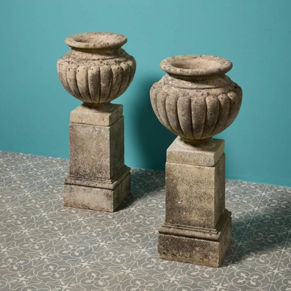 Pair of Weathered Gadrooned Composition Stone Urns on Bases